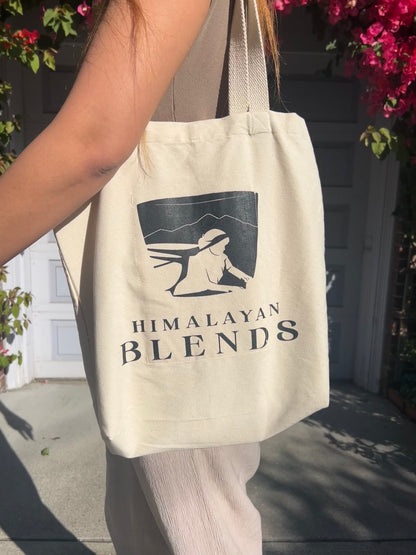 Model carrying Himalayan Blends signature canvas tote bag featuring minimalist mountain artwork